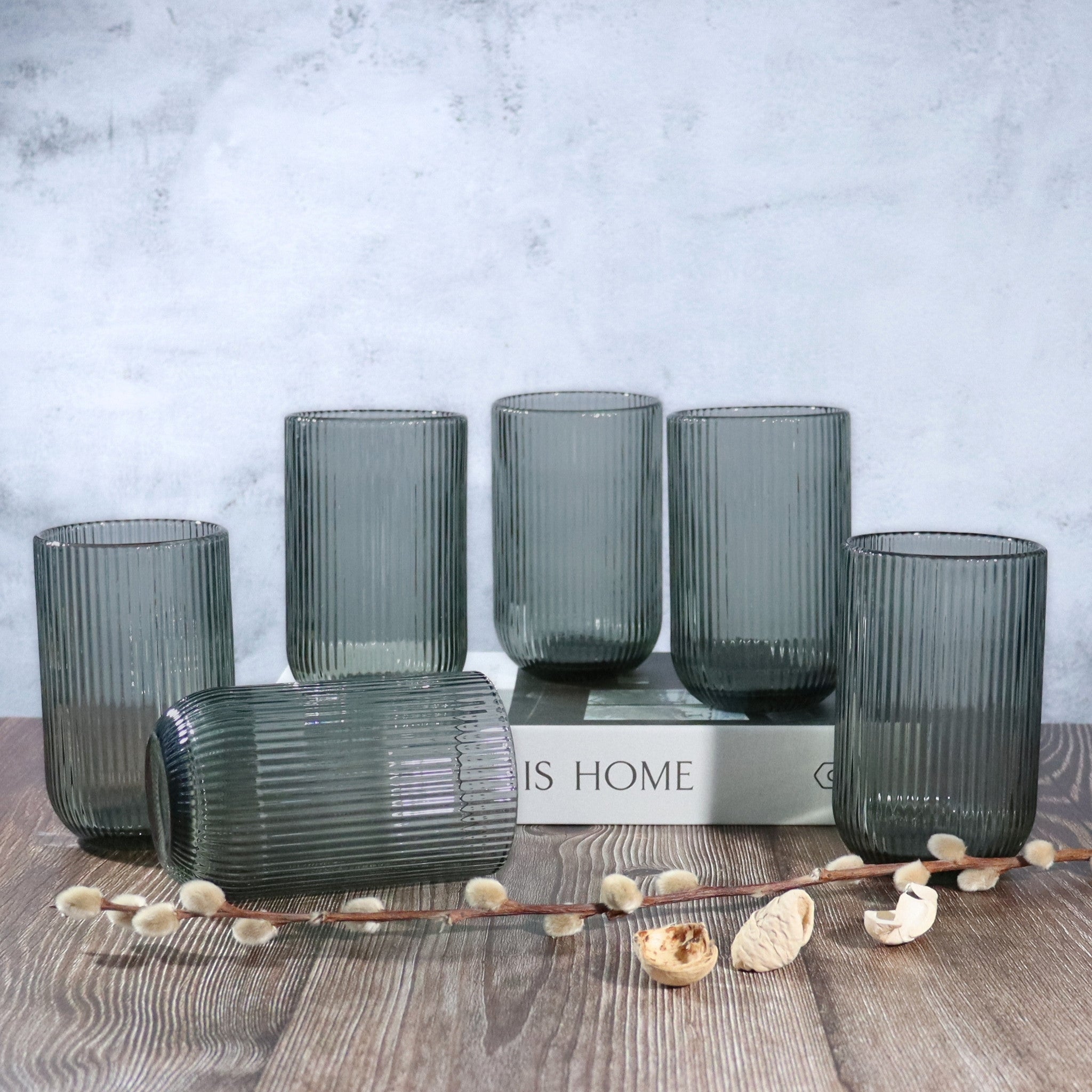 Set of ribbed glass tumblers on a wooden surface with a 'This Home' box in the background.