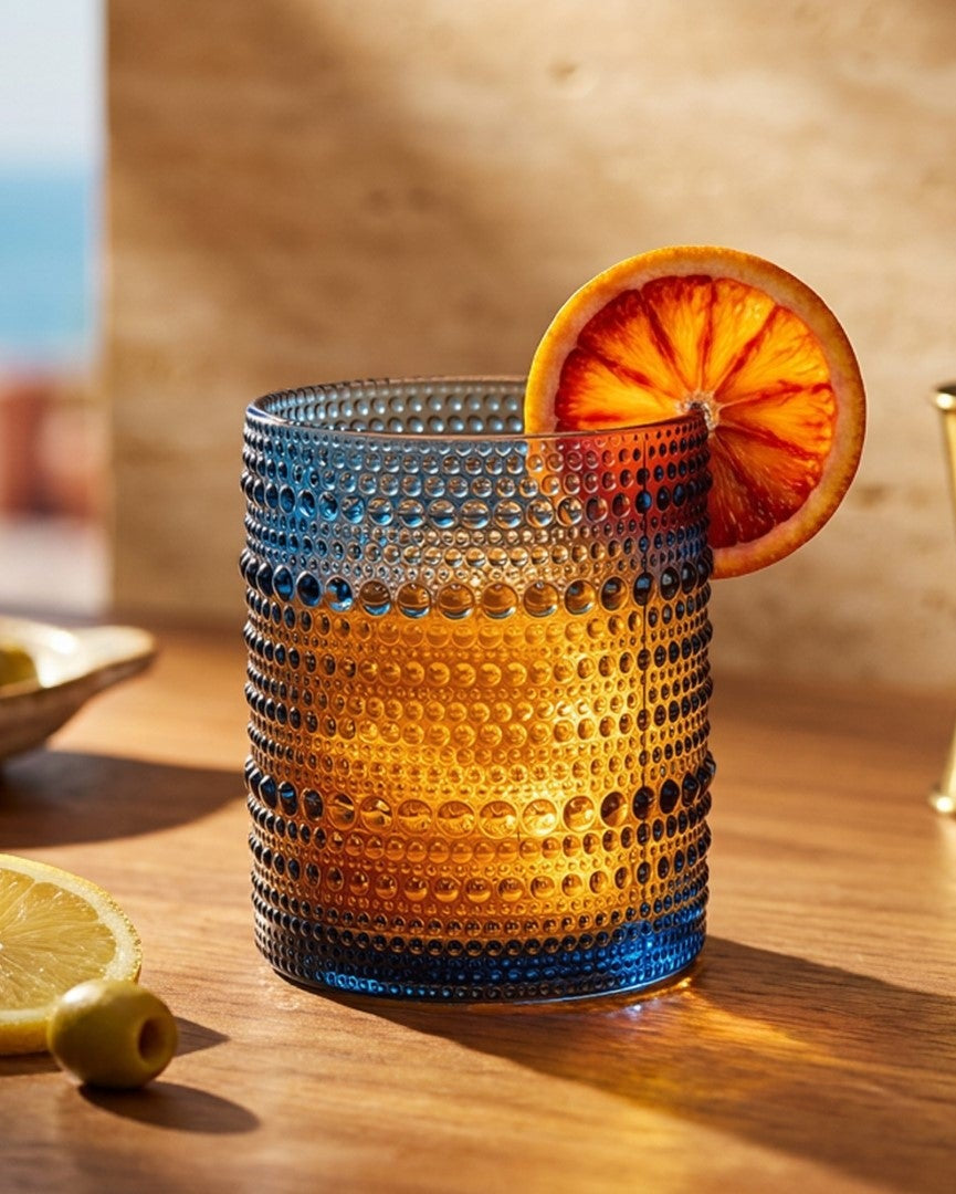 Set of blue textured glass tumblers on a wooden surface with a 'feels like home' book.