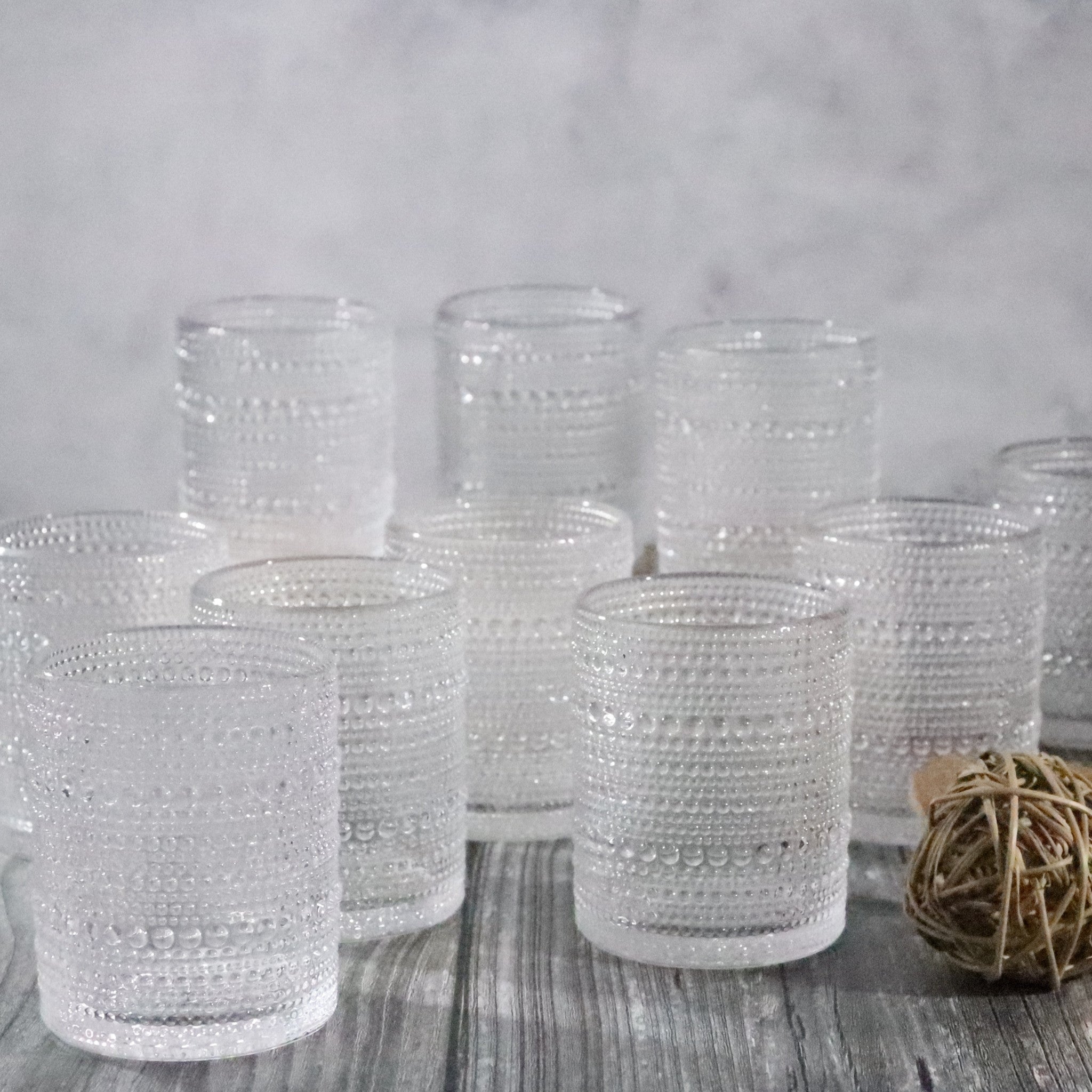 Set of clear textured glass tumblers on a wooden surface with a neutral background