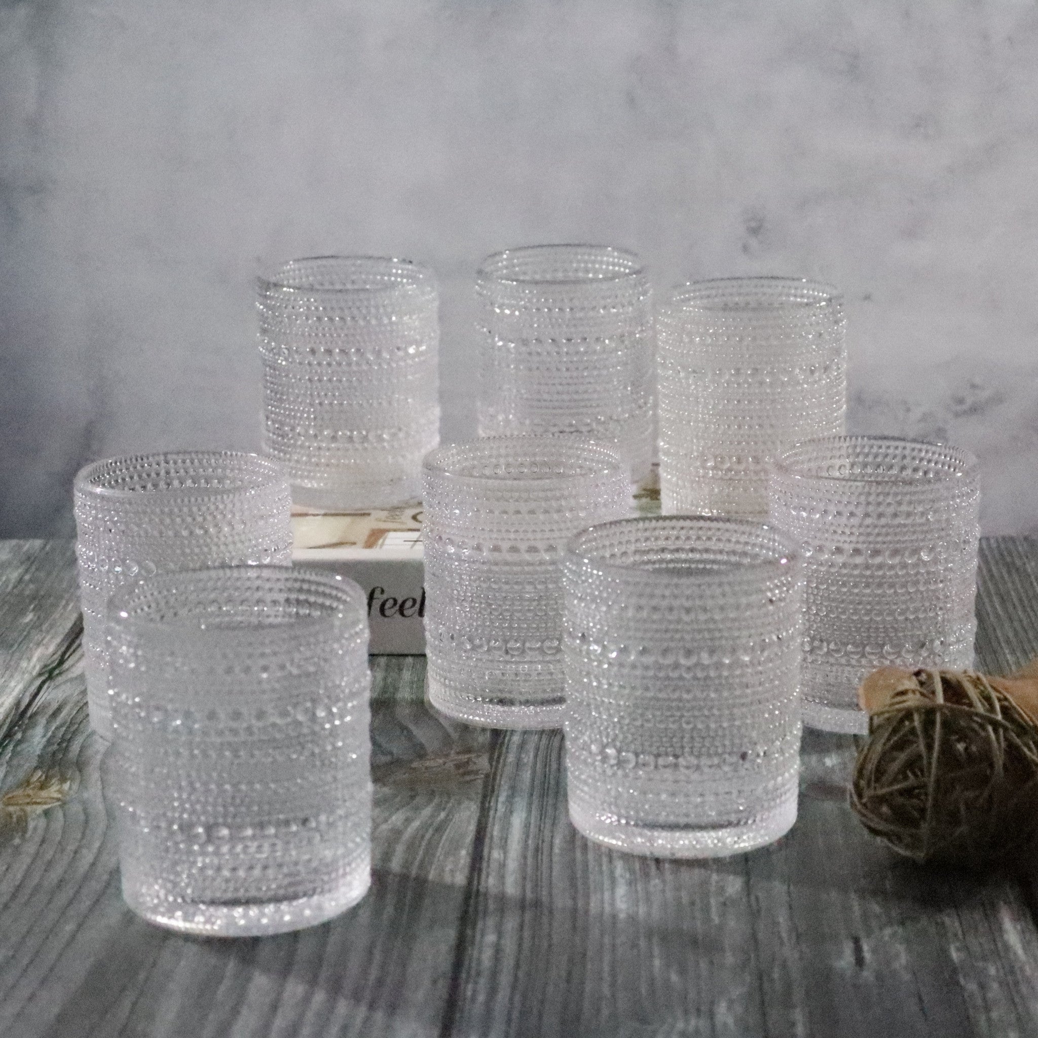 Set of textured clear glass tumblers on a wooden surface with a neutral background