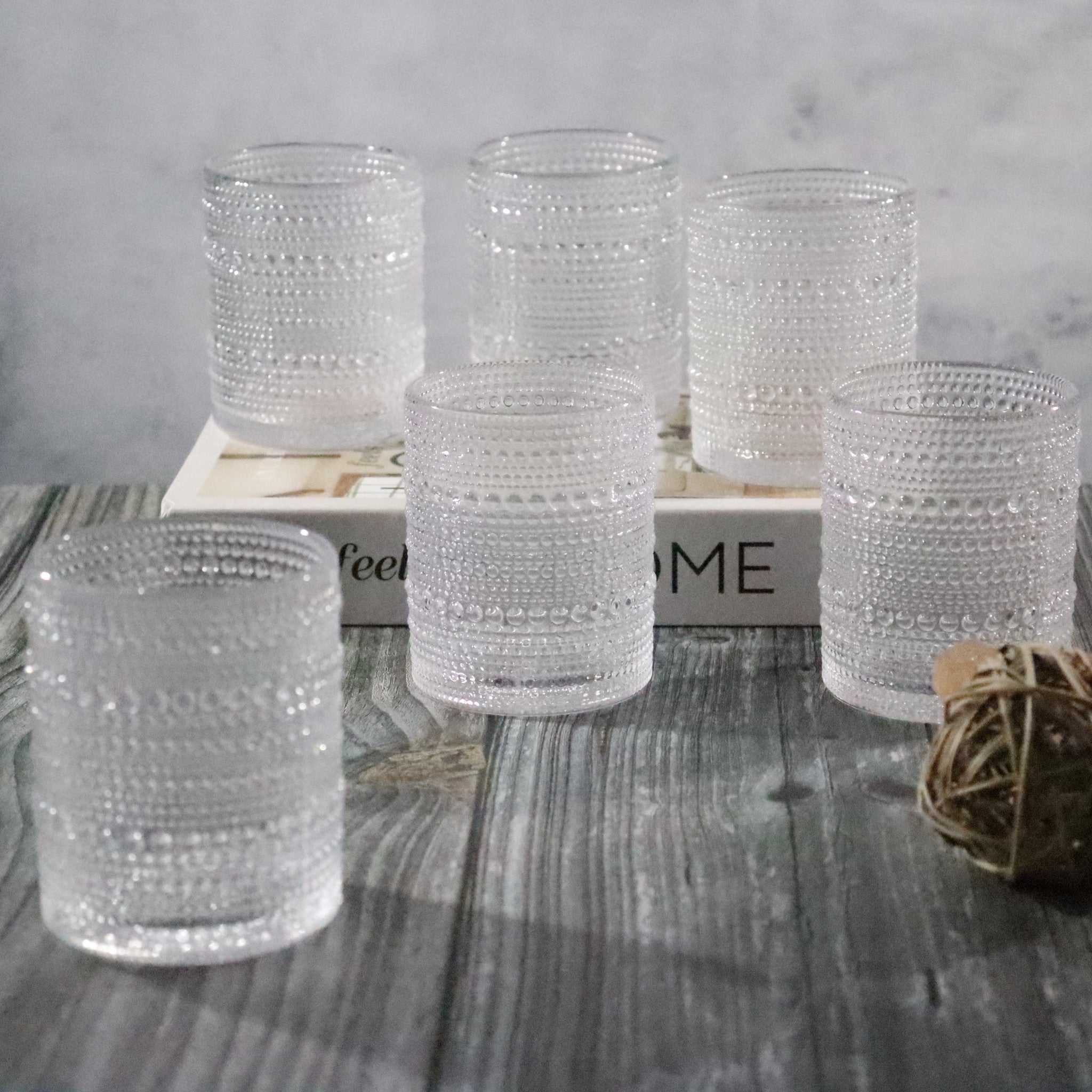 Set of beaded hobnail old fashioned tumblers on a wooden surface with a neutral background