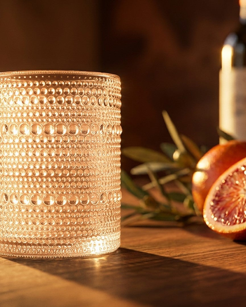 Two textured beaded hobnail old fashioned tumblers on a wooden surface with a marble background