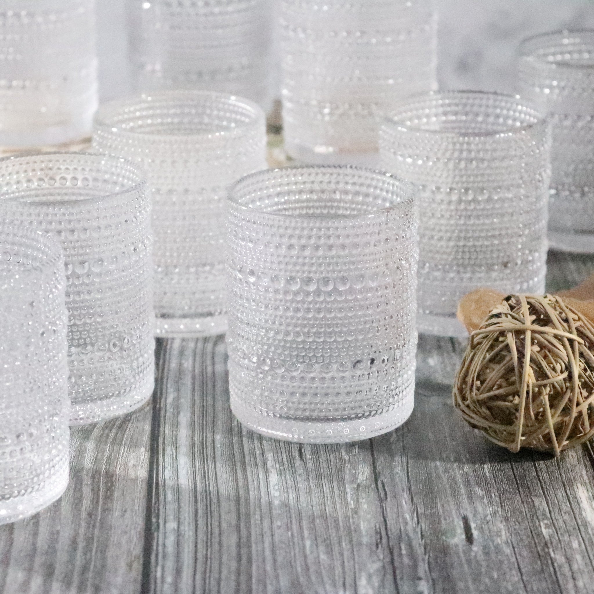 Set of textured beaded hobnail glasses on a wooden surface with a small bundle of twine.