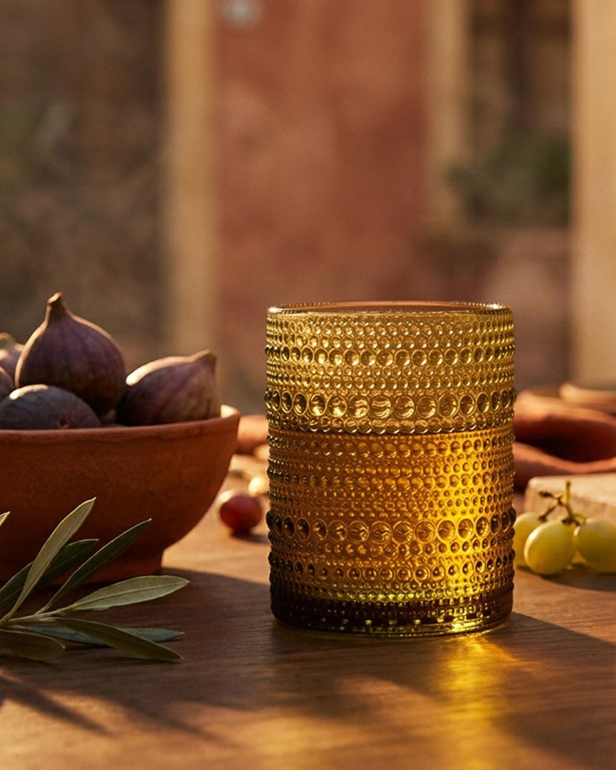 Gold textured glass on a wooden table with fruits and cutlery