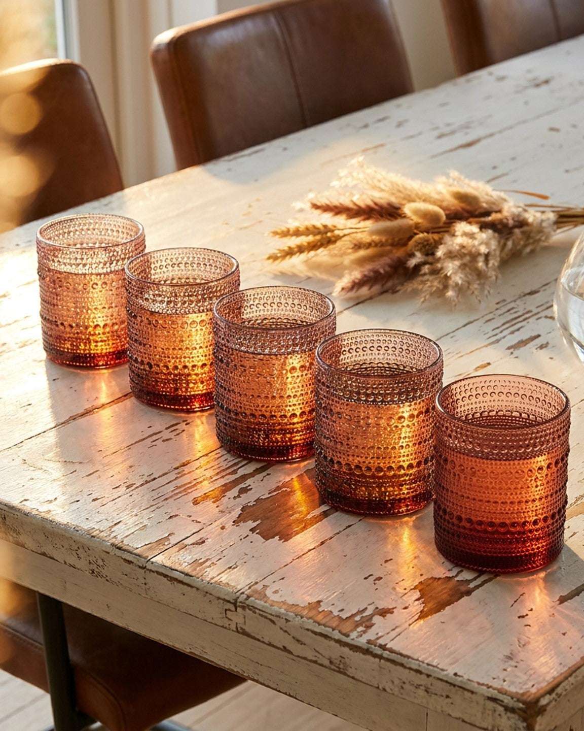purple textured glass votives on a white surface with decorative elements.