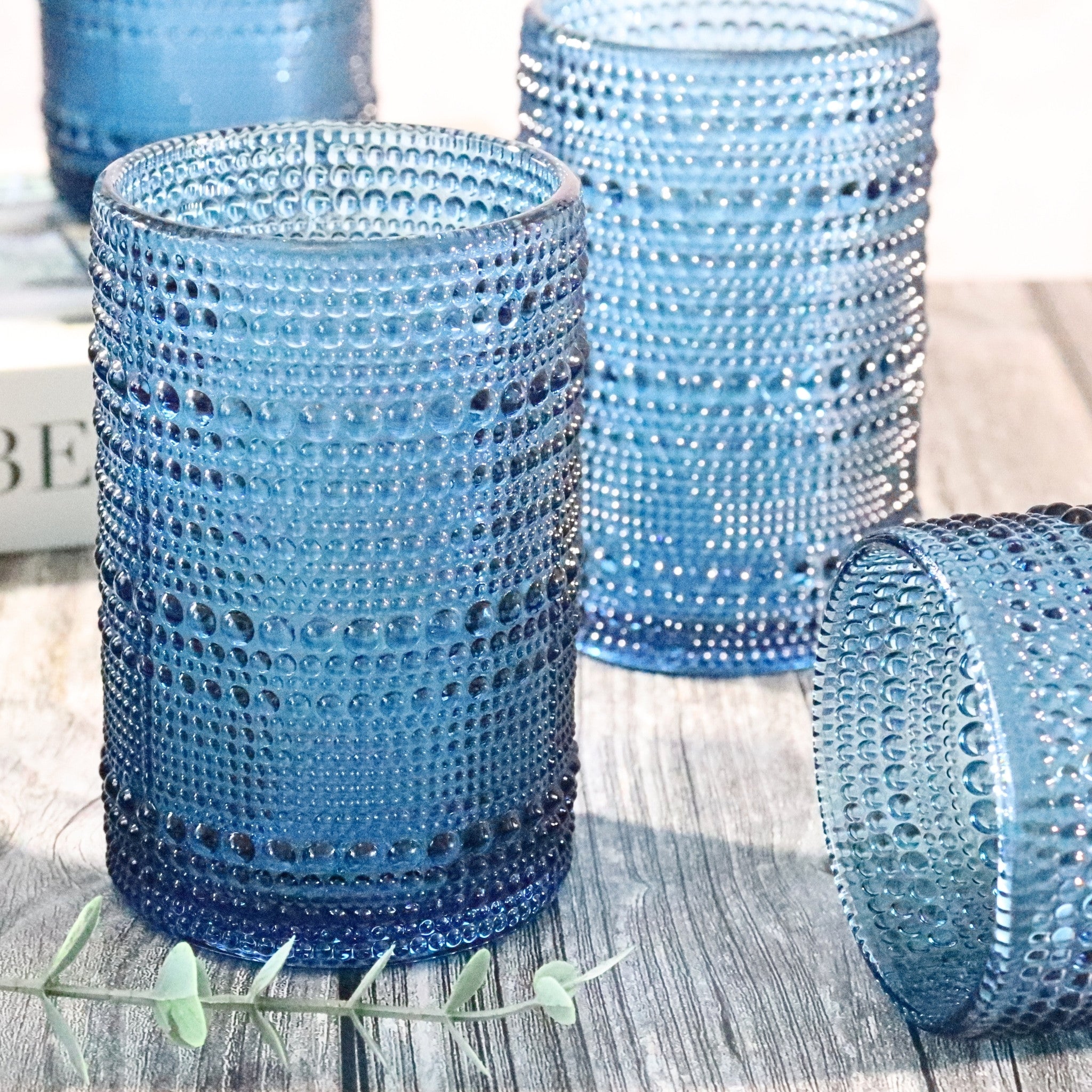 Set of blue hobnail jupiter bead glasses on a wooden surface.