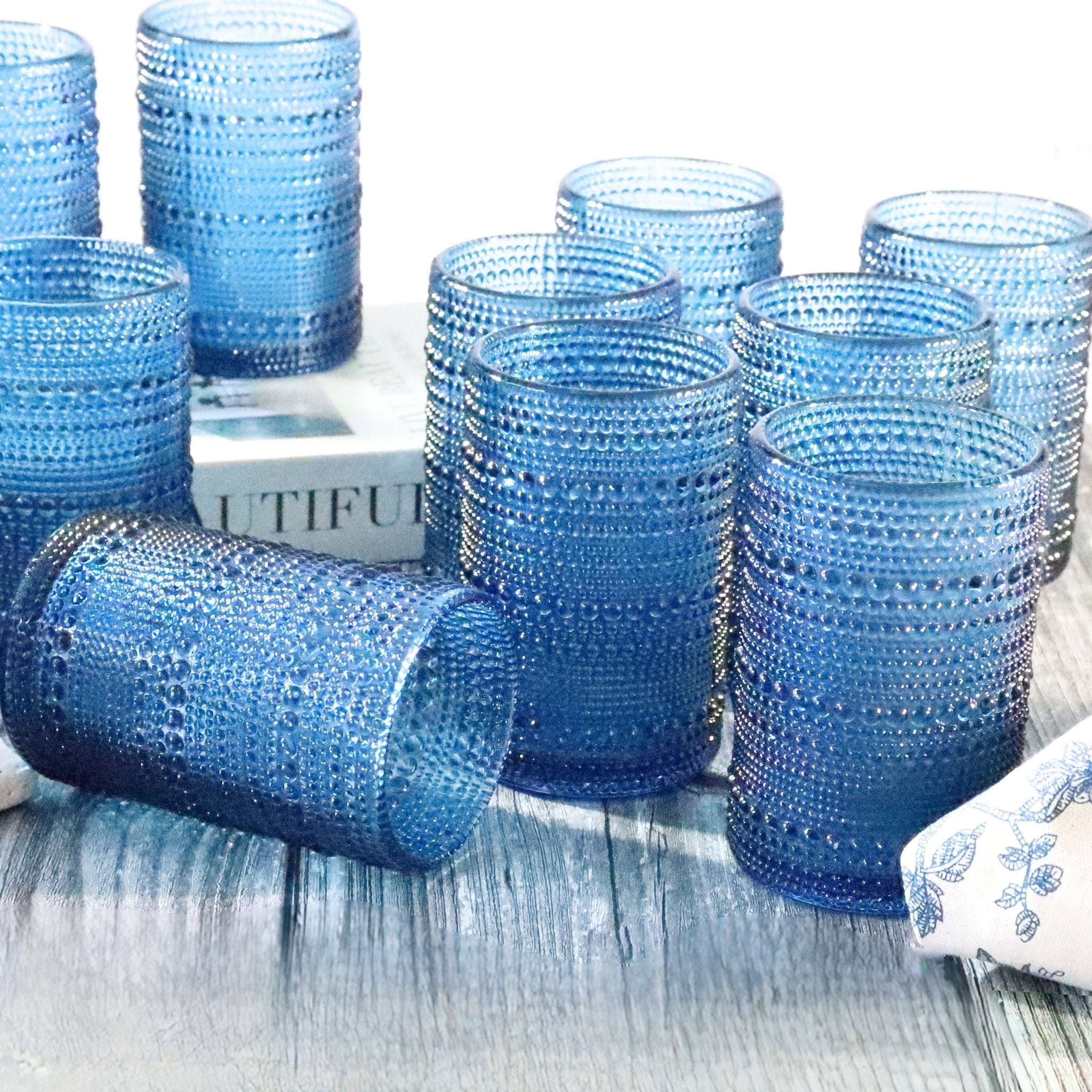 Set of blue textured glass tumblers on a wooden surface with a blurred background