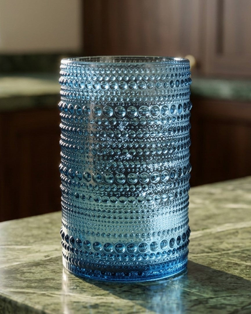 Set of blue textured glass tumblers on a wooden surface with a white background