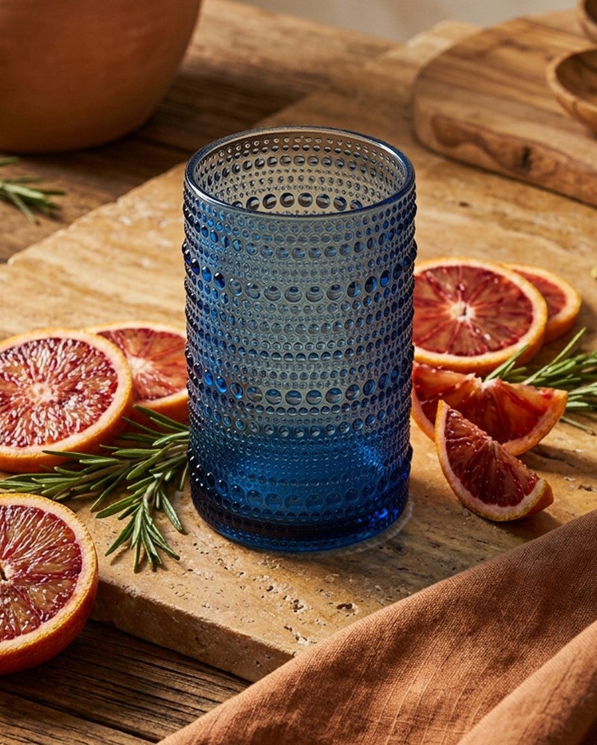 Set of blue textured glass tumblers on a wooden surface with a white background