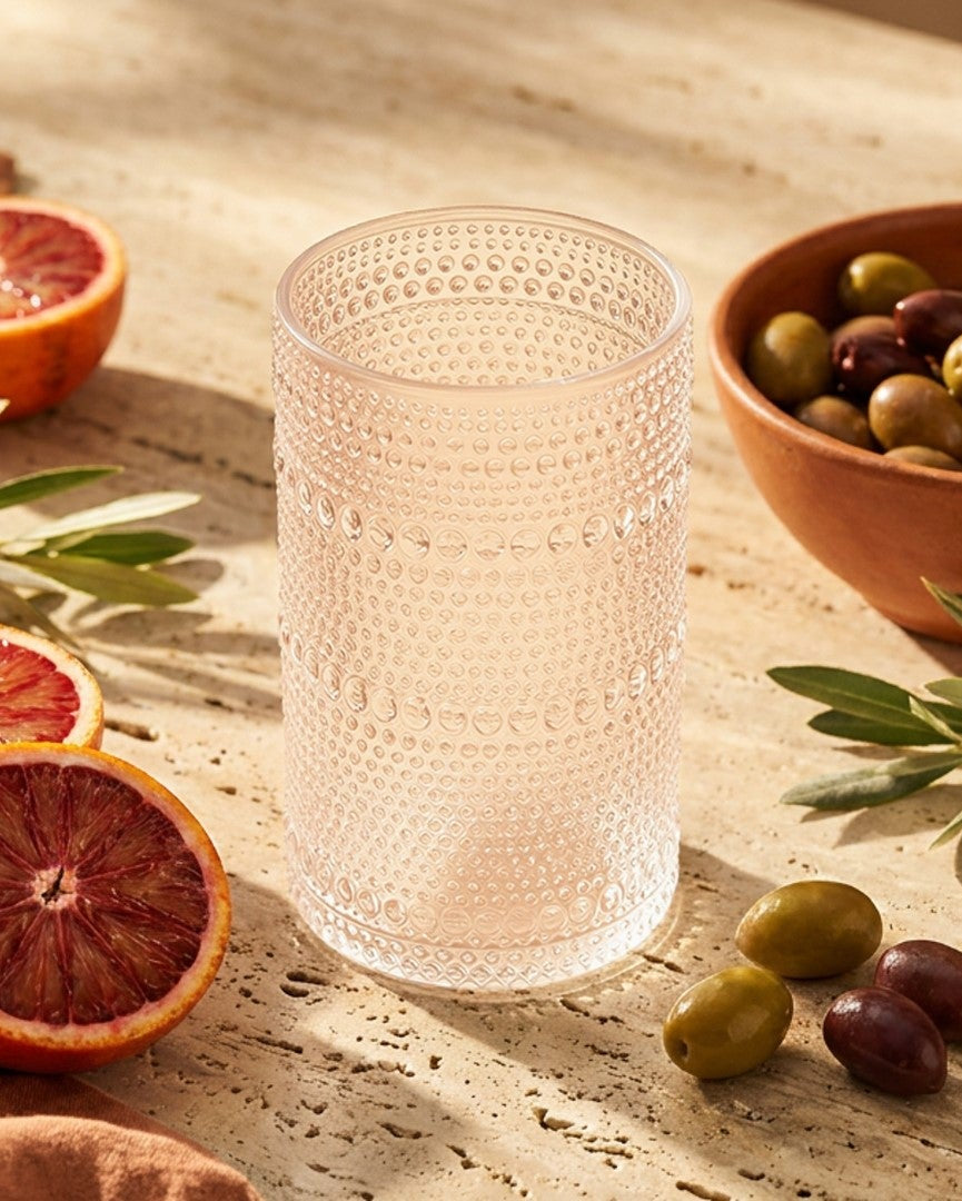 Set of beaded hobnail clear glass tumblers on a wooden surface with a neutral background