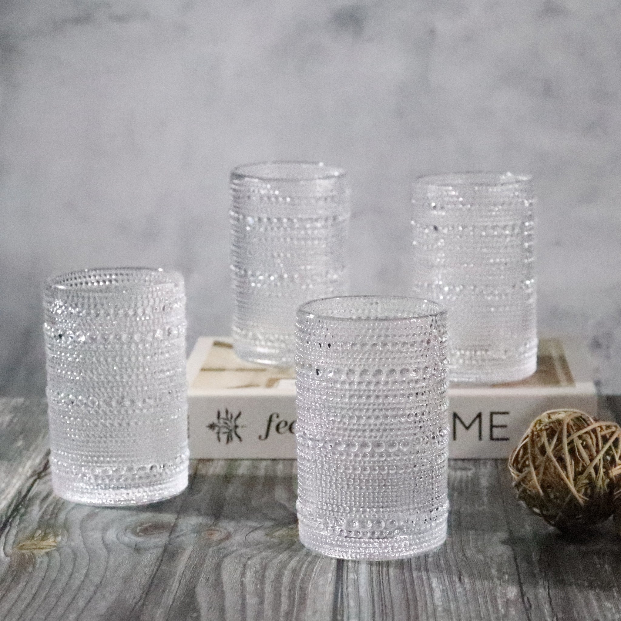 Set of four textured glass candle holders on a wooden surface with a neutral background