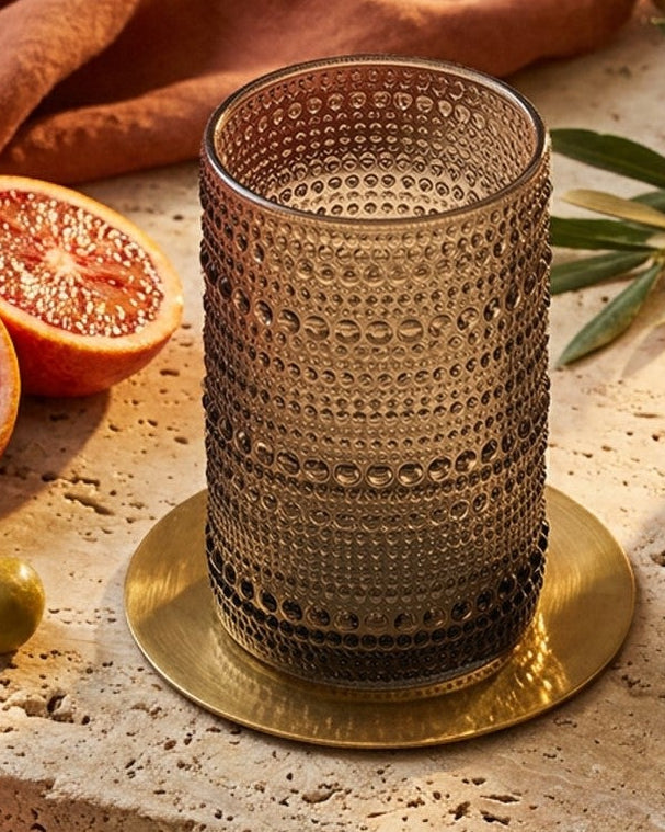 Set of grey hobnail jupiter bead glass tumblers on a wooden surface with a marble background