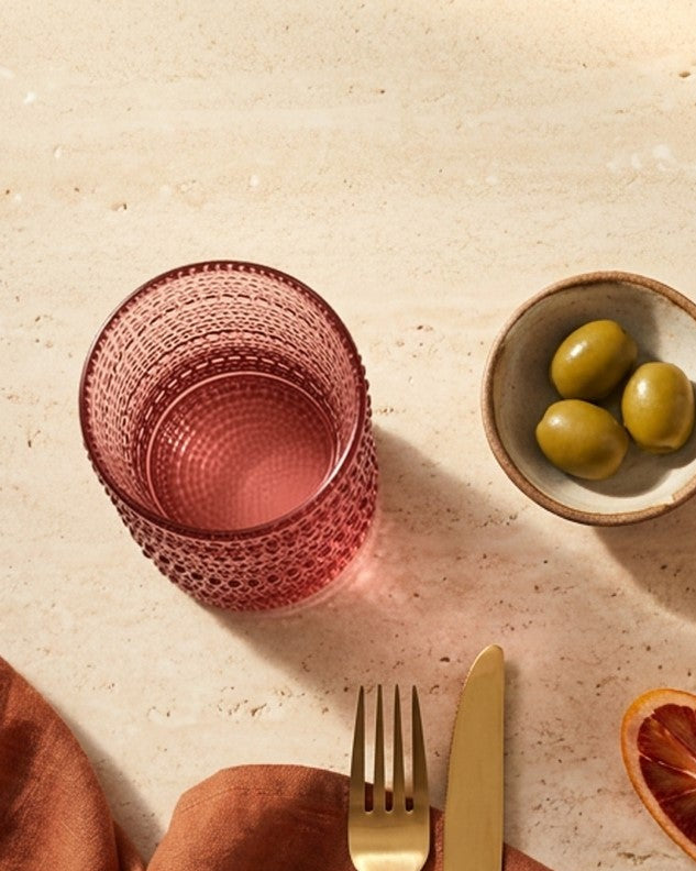 Set of purple textured glass tumblers on a white surface with decorative elements.