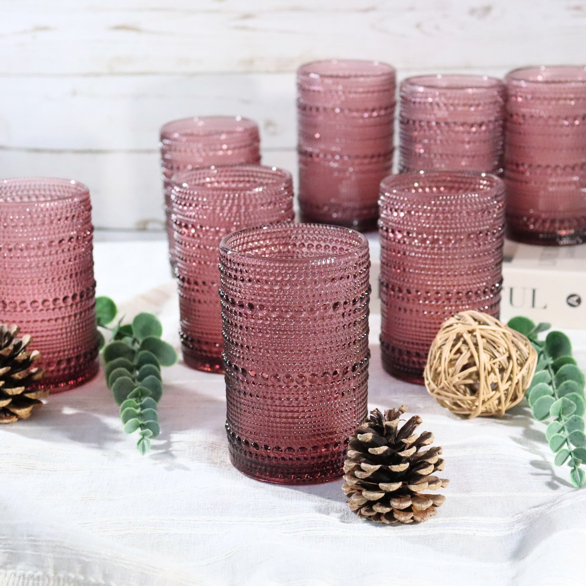 Set of purple textured glass tumblers on a white surface with decorative elements.