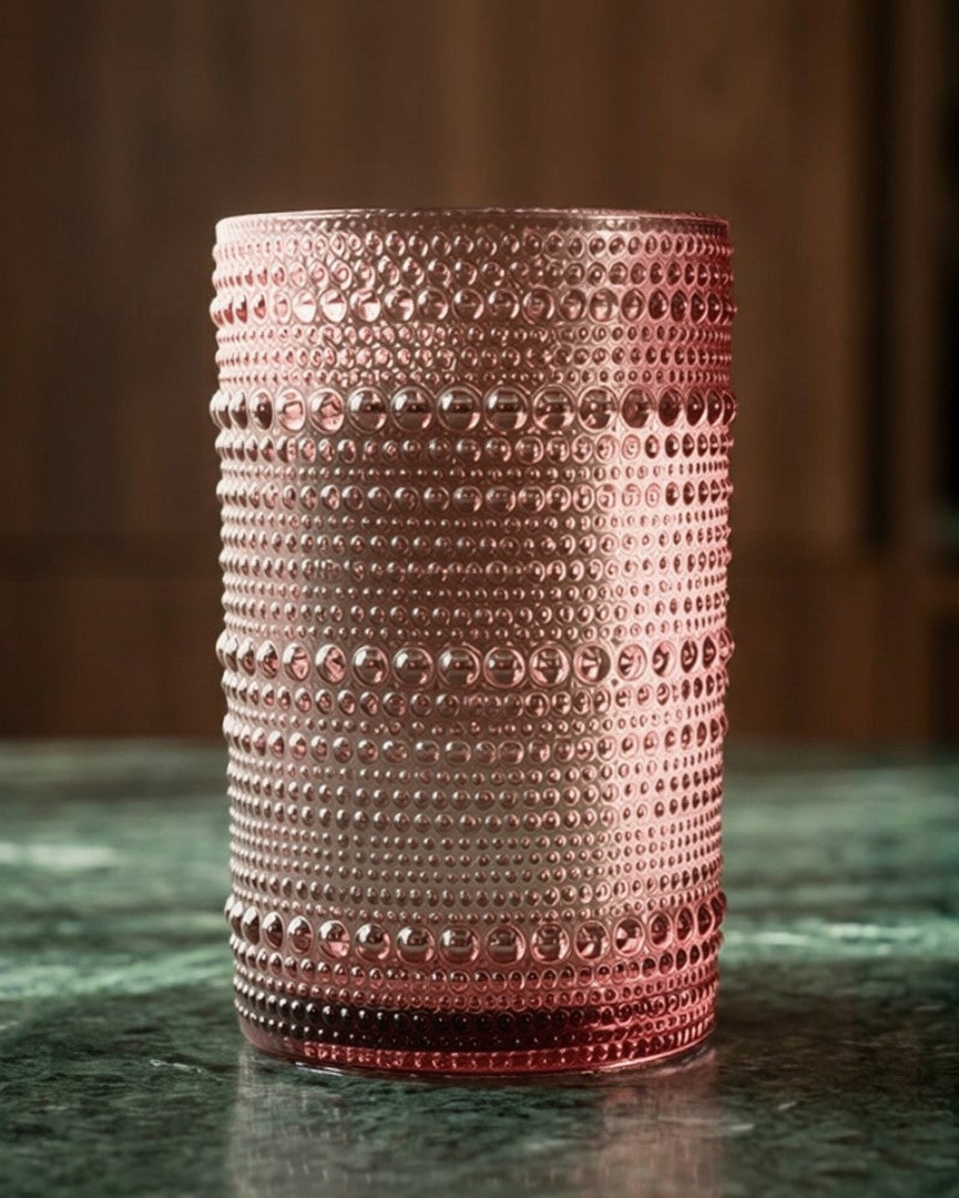 Set of four purple textured glass tumblers on a white surface with a wooden background.