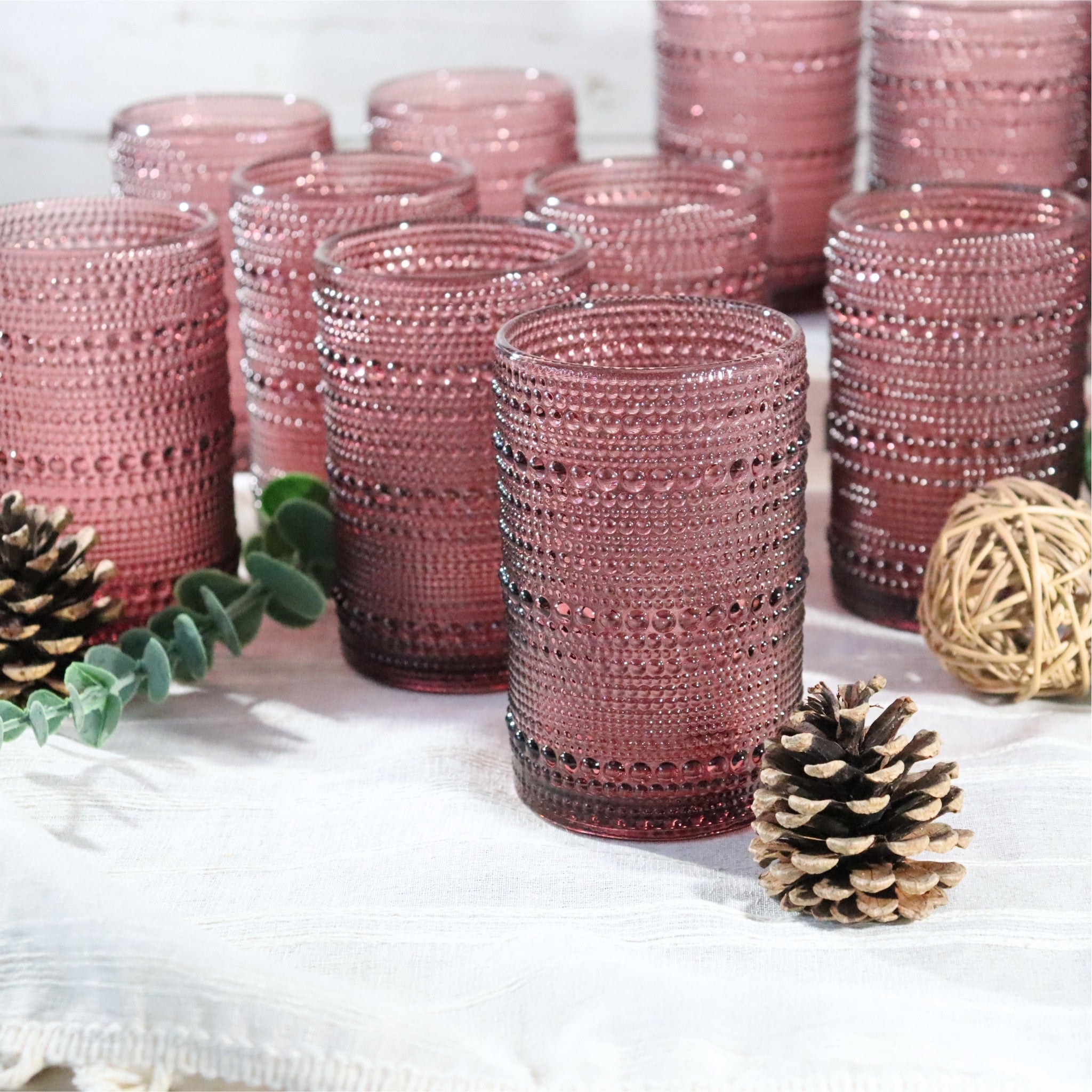 purple textured glass tumblers on a white surface with decorative elements.