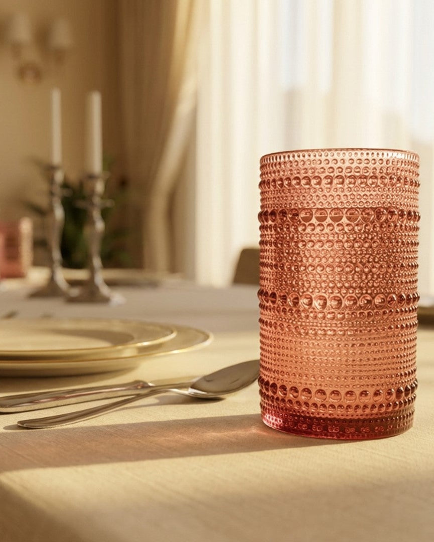Set of four textured purple glasses on a white surface with a light wooden background