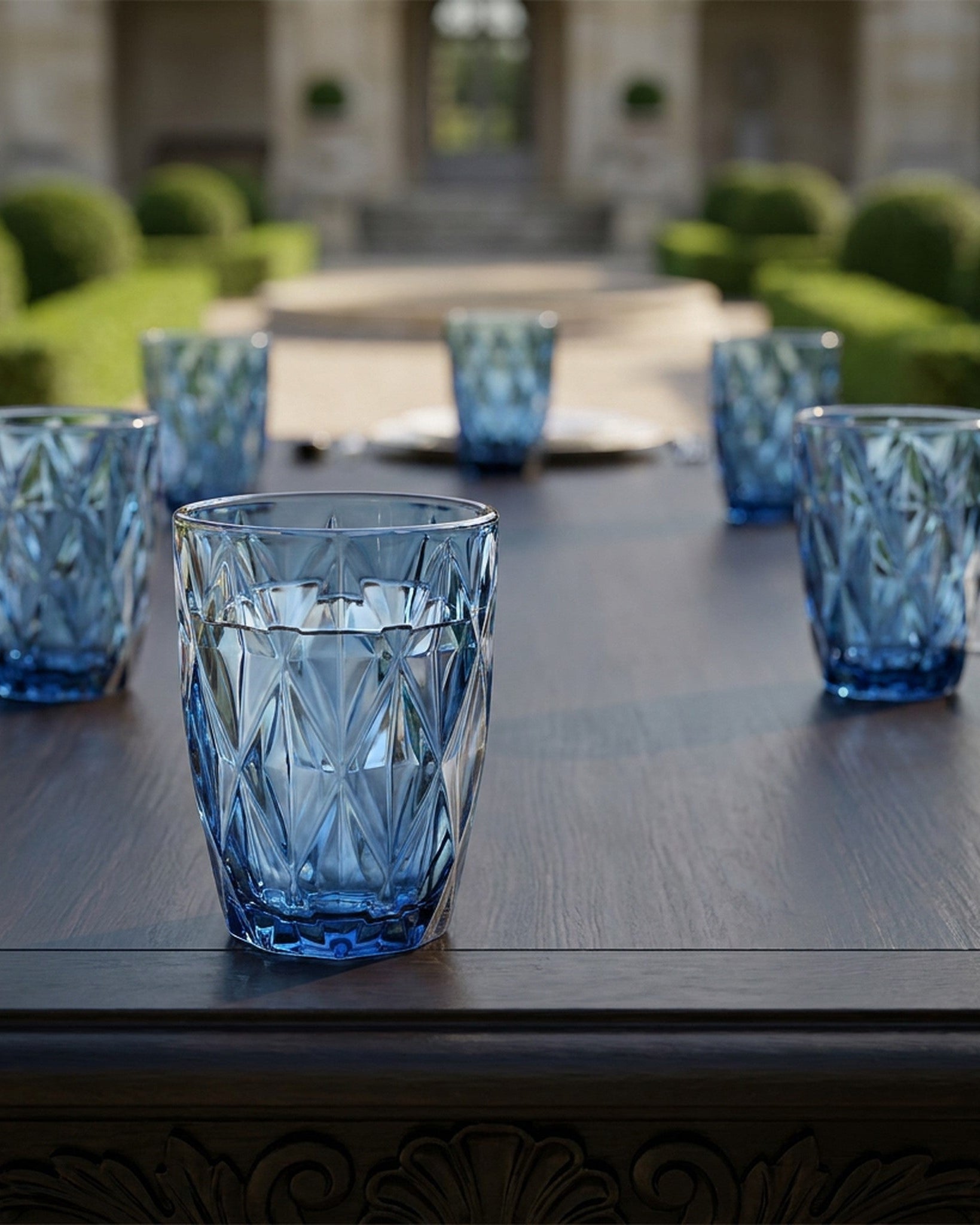 Set of blue glass tumblers on a white surface with a wooden background
