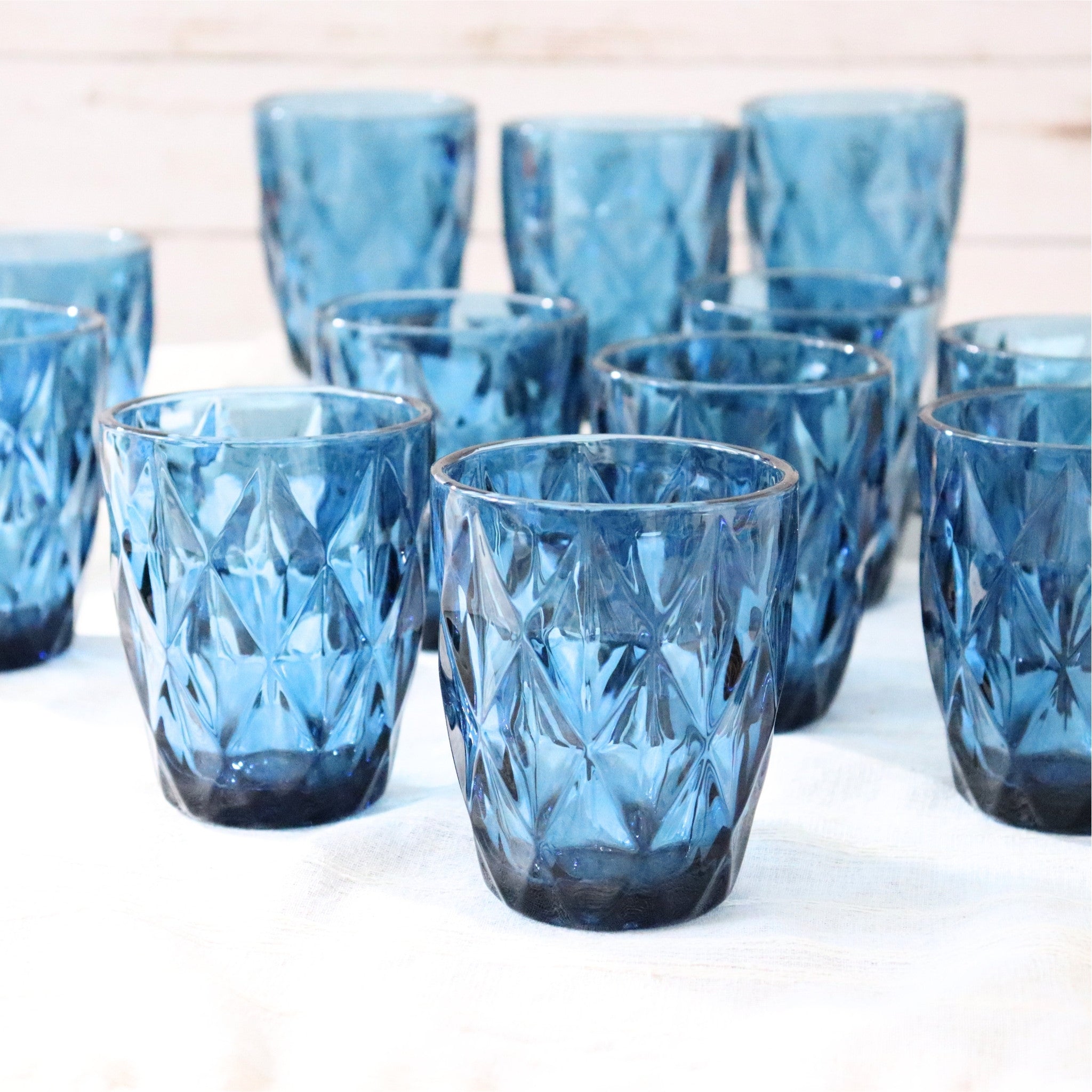 Set of blue glass tumblers with a textured design on a white surface.