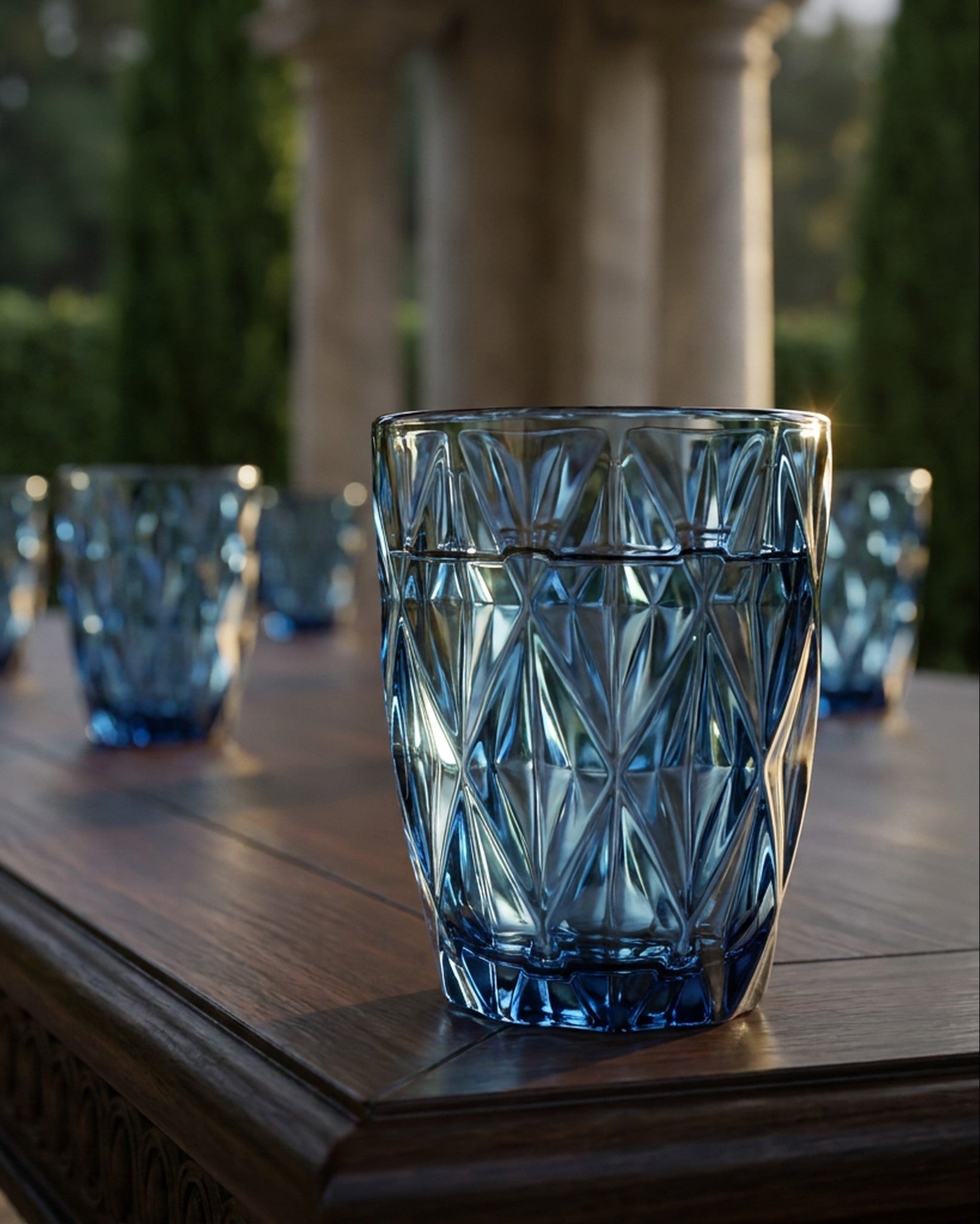 Set of blue glass tumblers on a white surface with decorative elements.