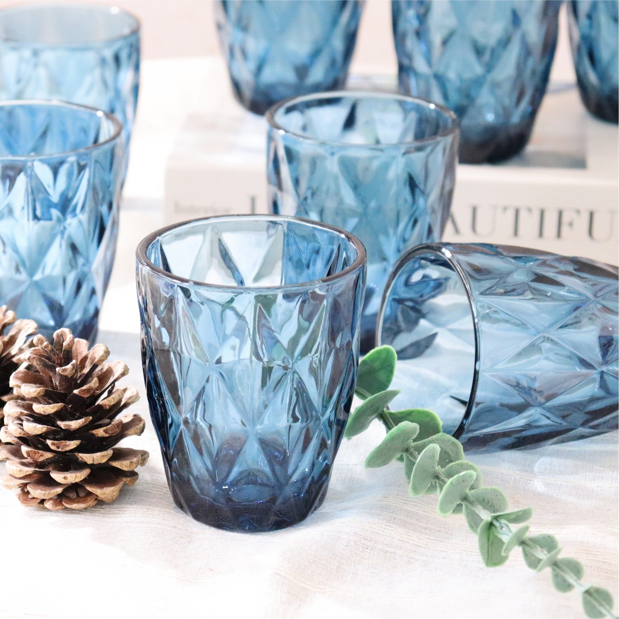 Set of blue textured glass tumblers on a light surface with decorative elements.