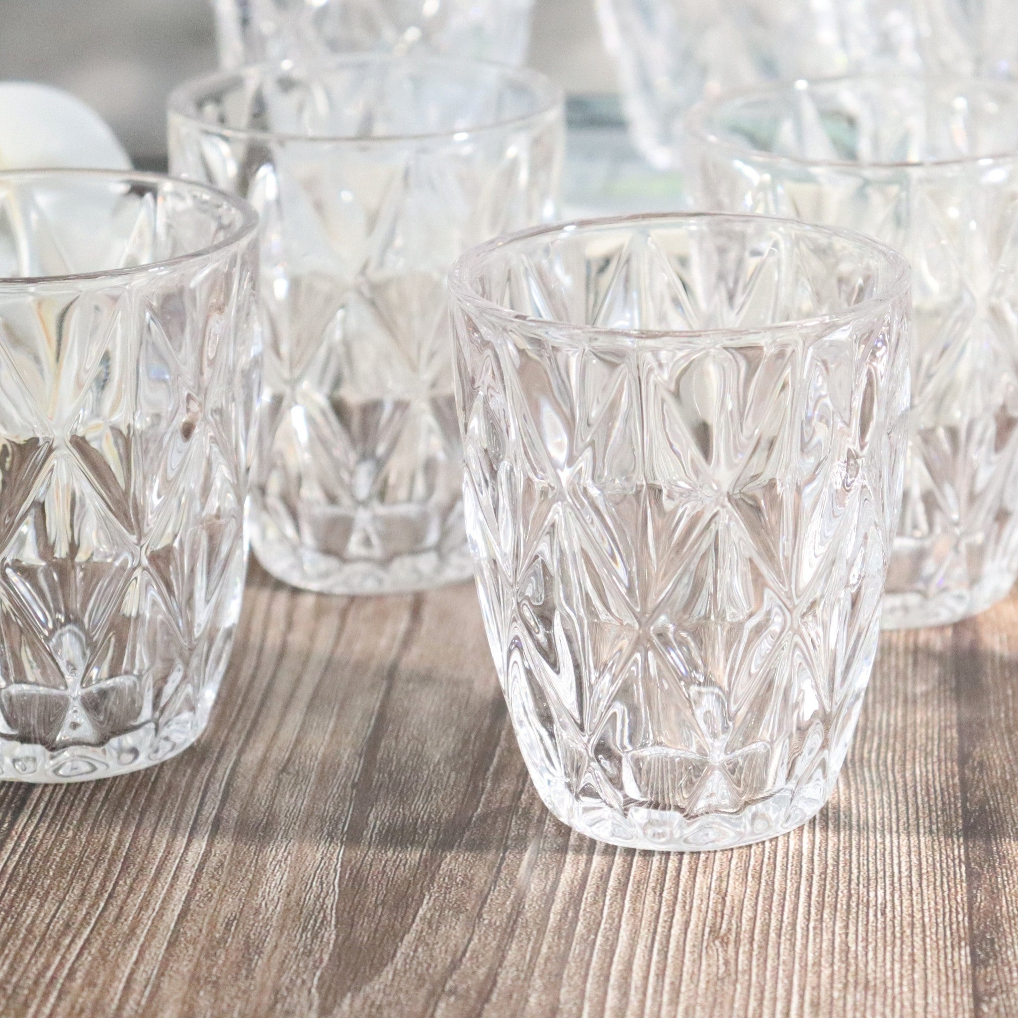 Set of clear glass tumblers with diamond pattern on a wooden surface