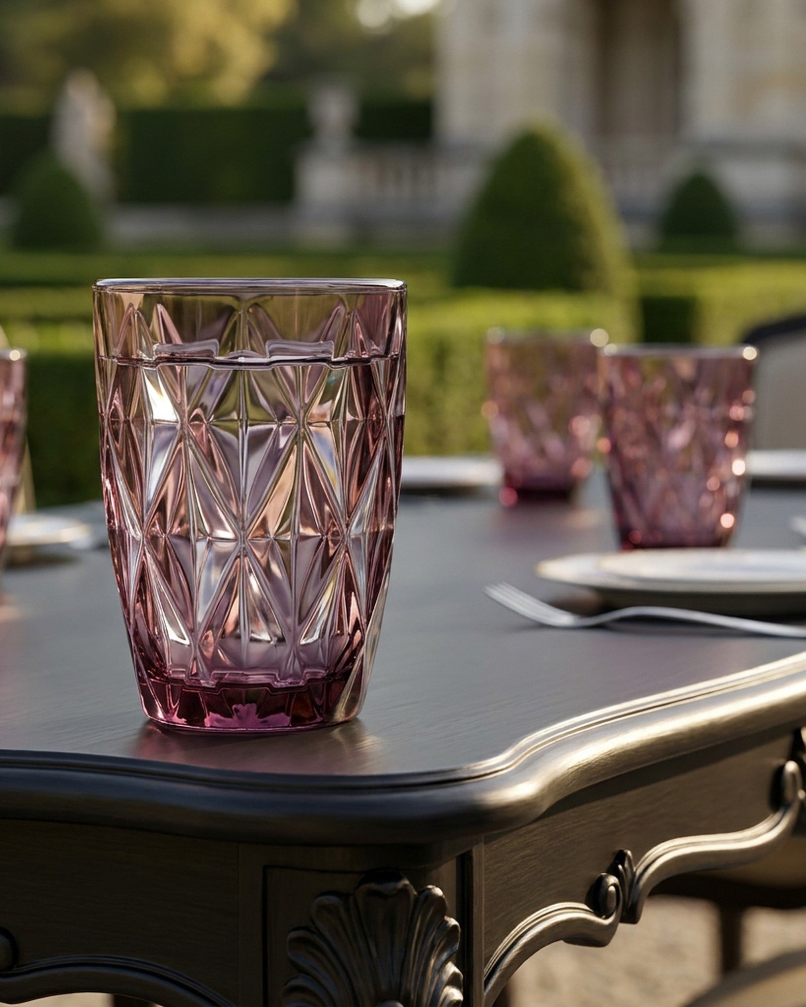 Pink crystal glasses on a table with a blurred garden background