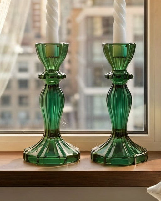 Green candle holders on a windowsill with cityscape view