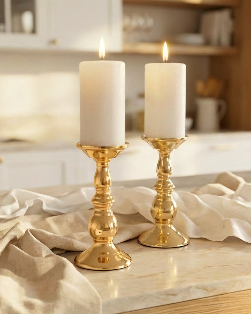 Gold candlesticks with white candles on a kitchen counter