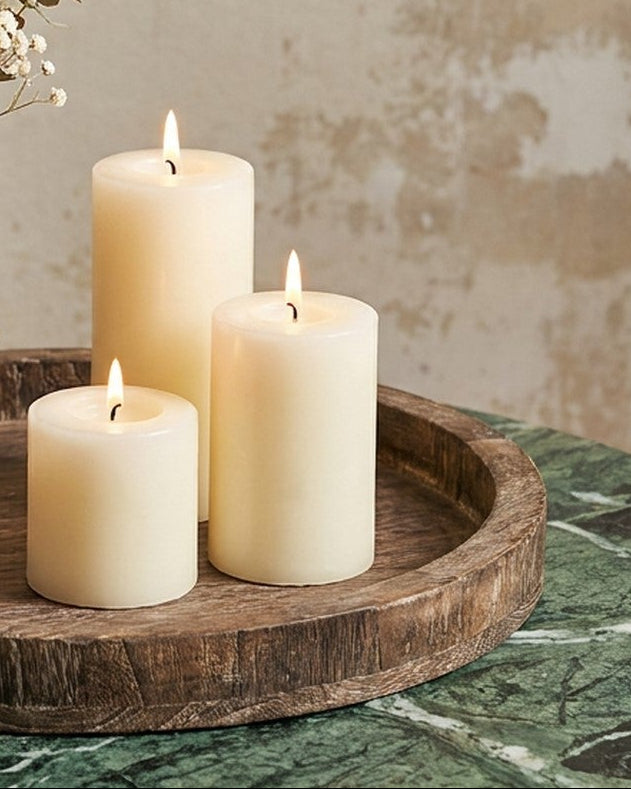 Decorative setup with candles and a vase of flowers on a wooden tray.