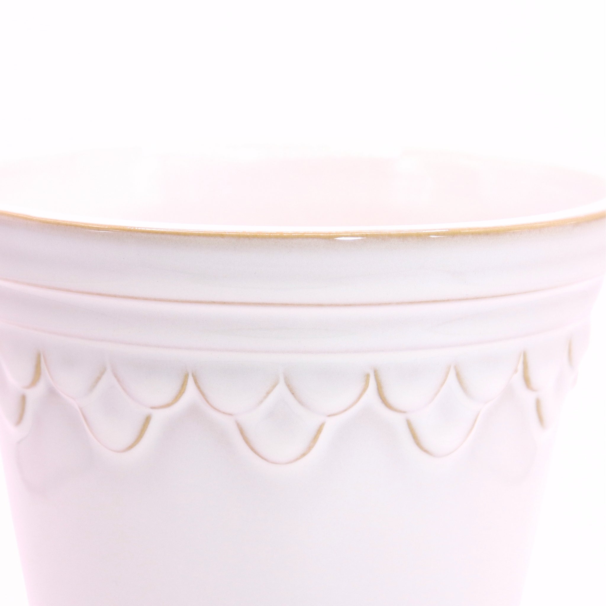 Close-up of a white ceramic planter with scalloped edge design on a white background