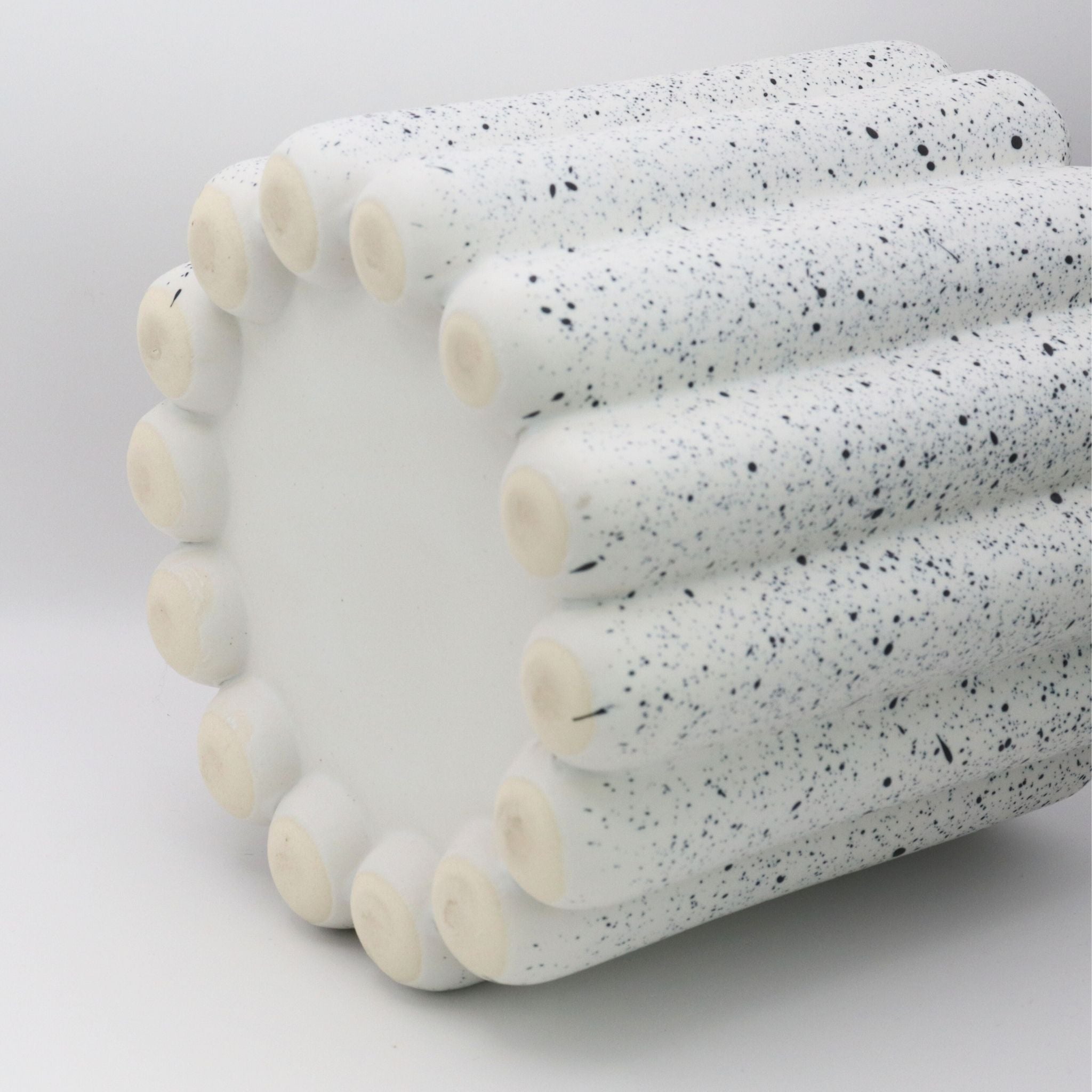 Speckled ceramic cylindrical object on a white background