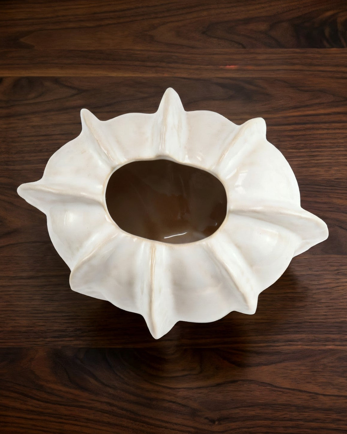 White ceramic vase with textured surface on a wooden surface