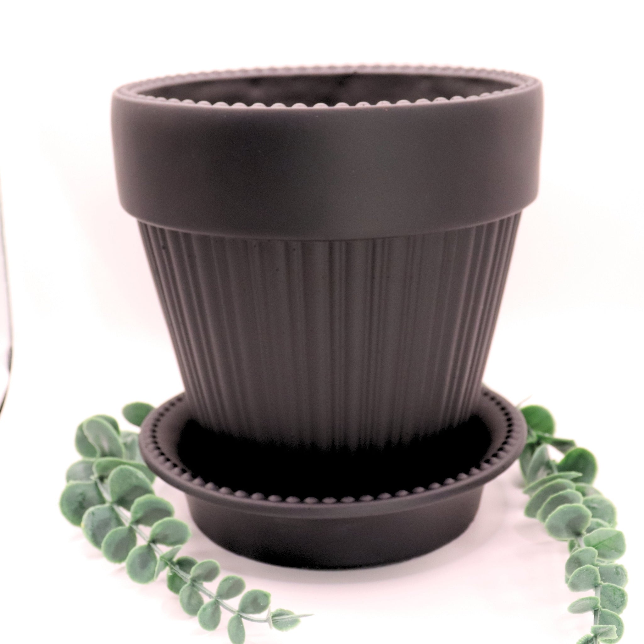 Black ribbed pot with matching saucer on a white background