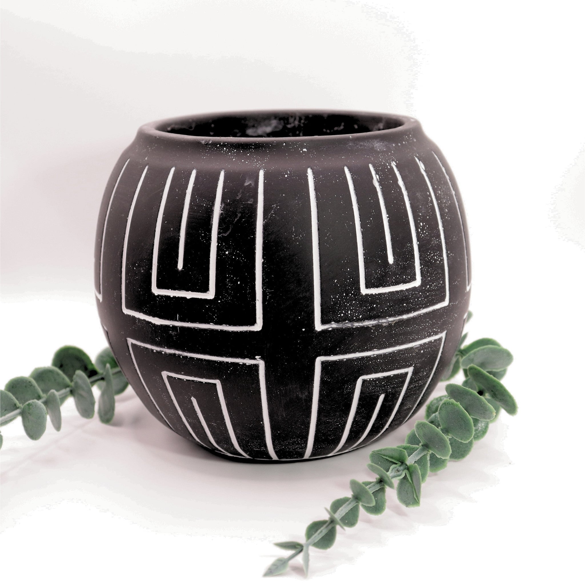 Black ceramic pot with geometric patterns on a white background