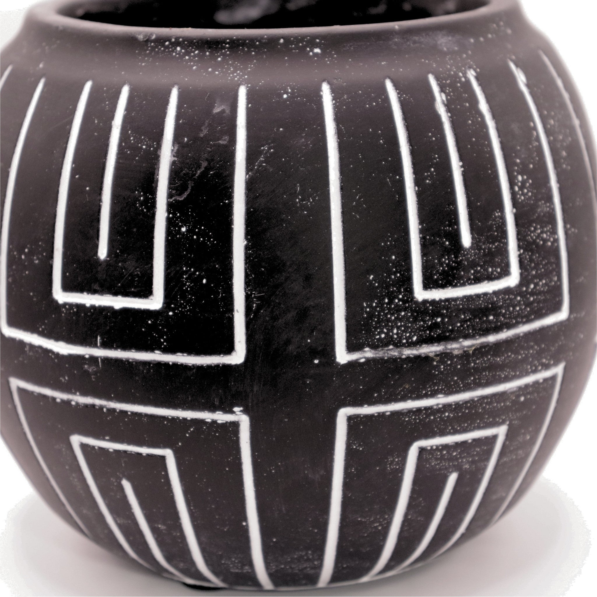 Black ceramic vase with white geometric patterns on a light background