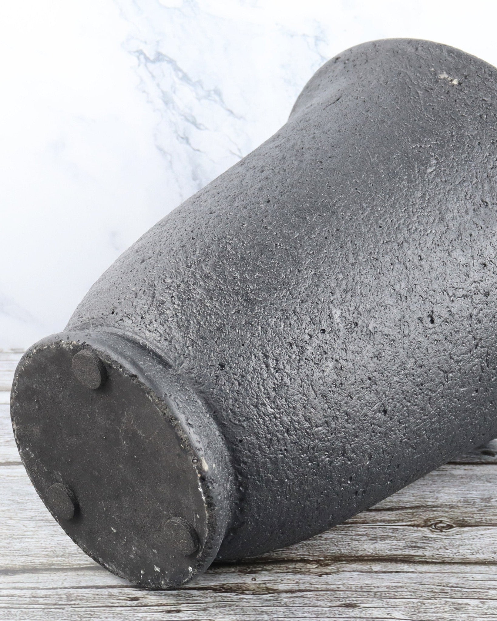 Concrete pipe on a wooden surface with a light gray background