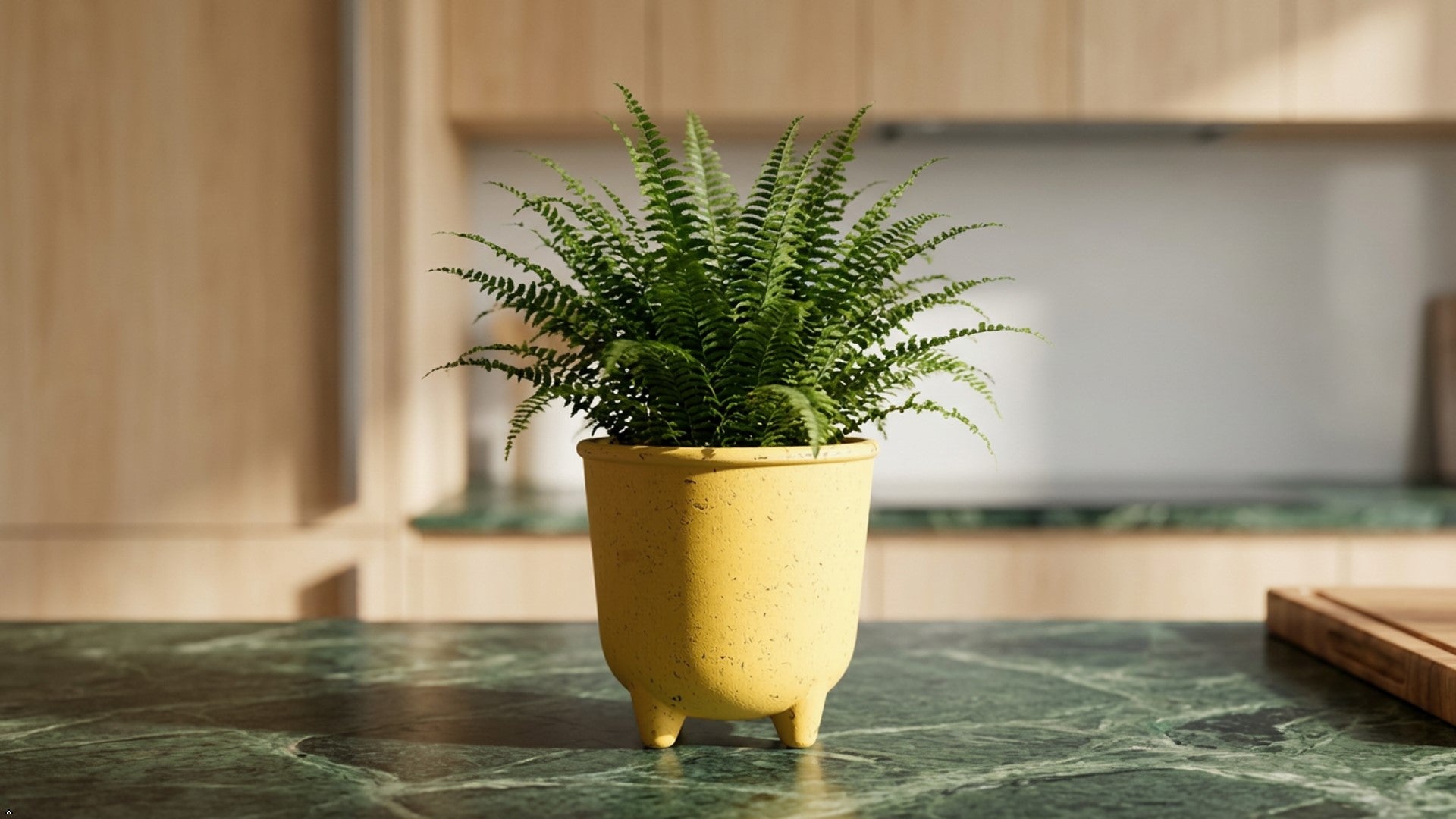 Yellow ceramic pot with textured surface on a wooden surface against a gray wall.