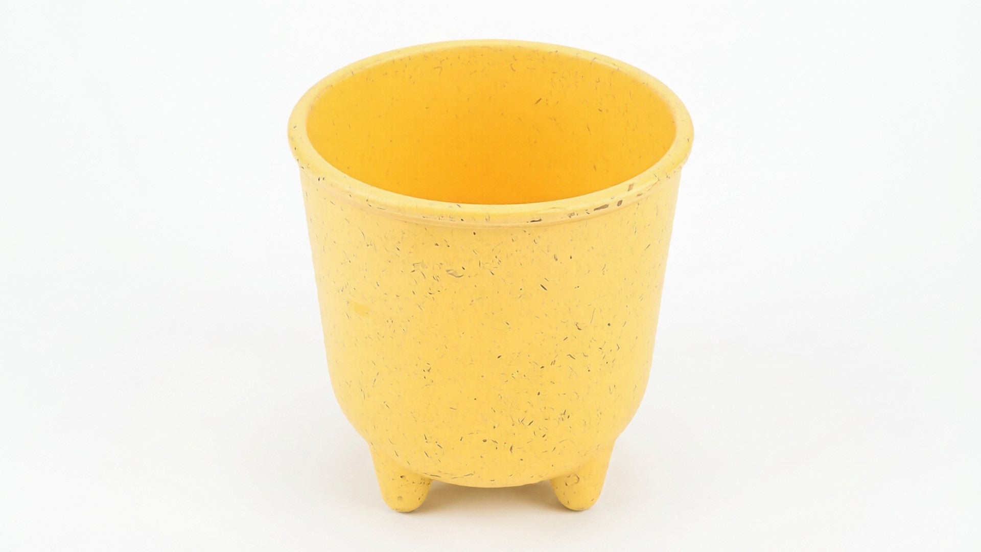 Yellow ceramic pot with speckled texture on a wooden surface