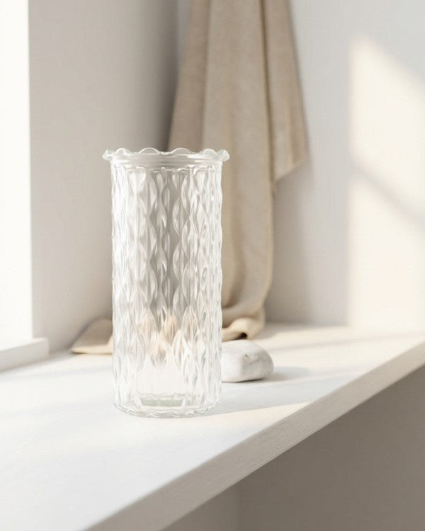 Clear glass vase on a windowsill with soft lighting