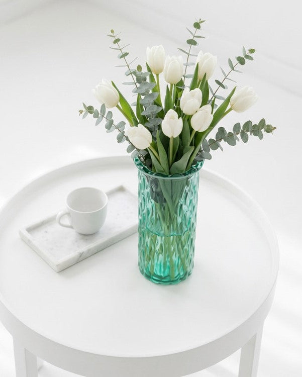 green glass vase on a shiny white table