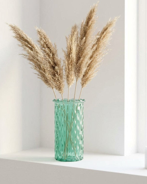 Green vase with dried pampas grass on a windowsill