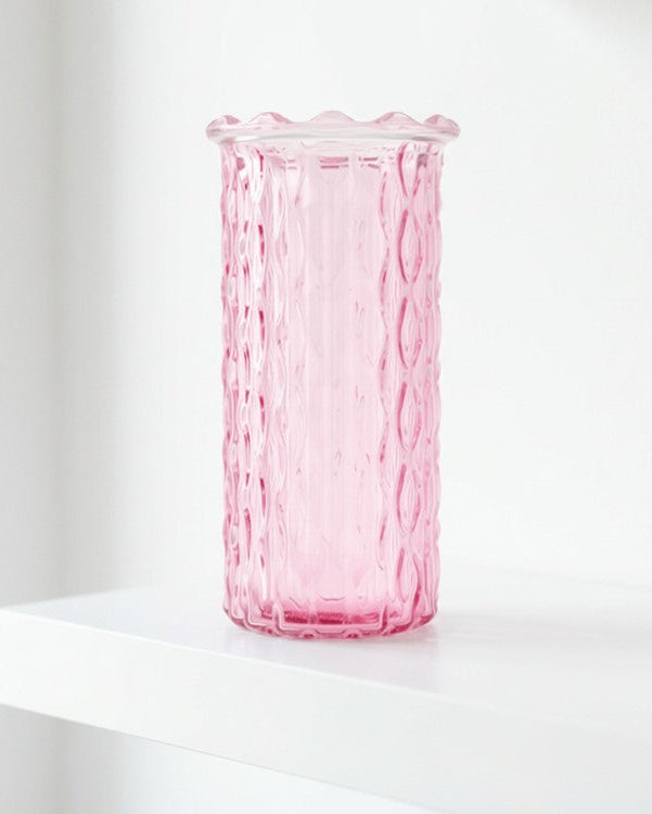 Pink glass vase on a white surface with a white background