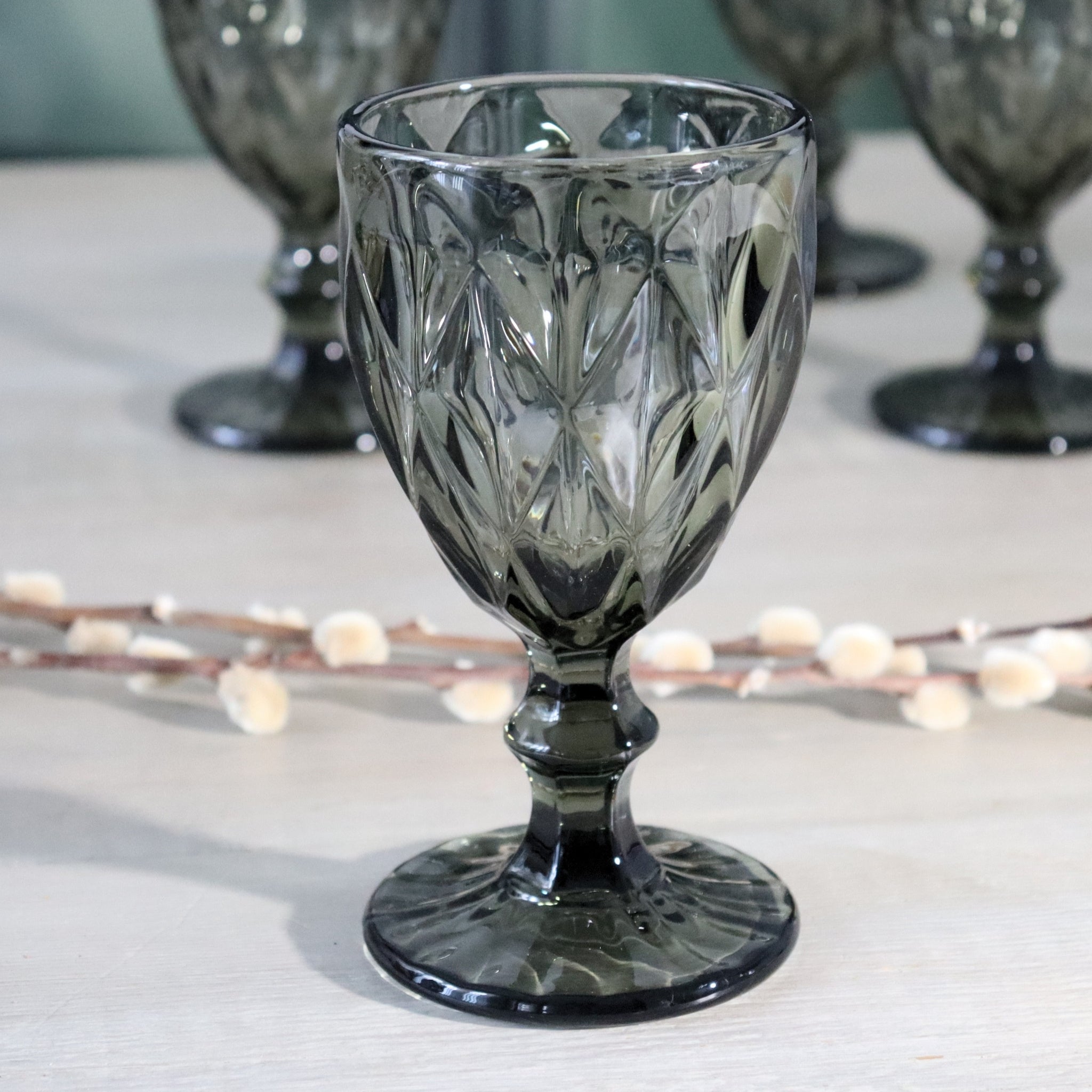 Decorative glass wine goblet with intricate patterns on a light surface.