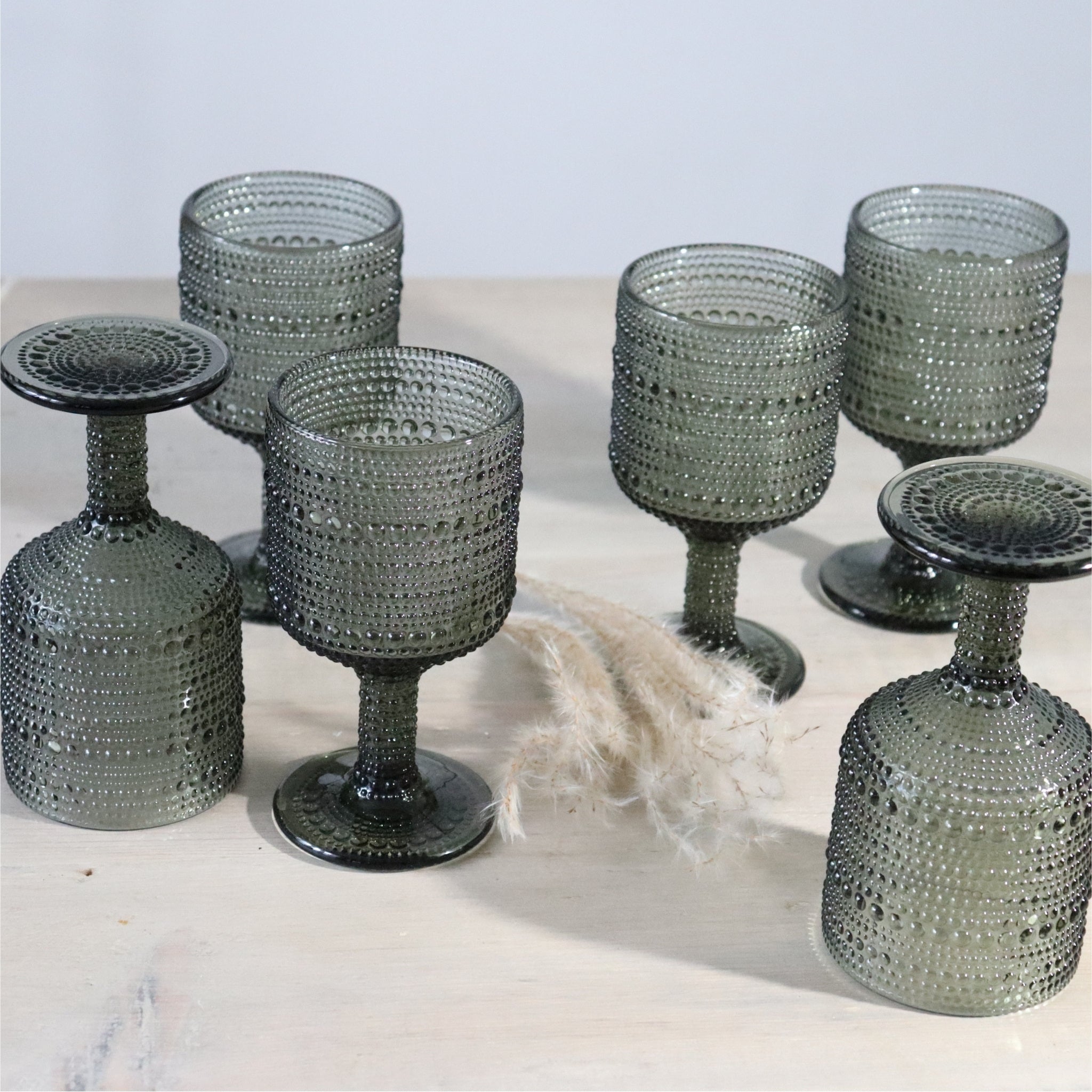 Set of gray textured glass goblets on a light surface with a neutral background