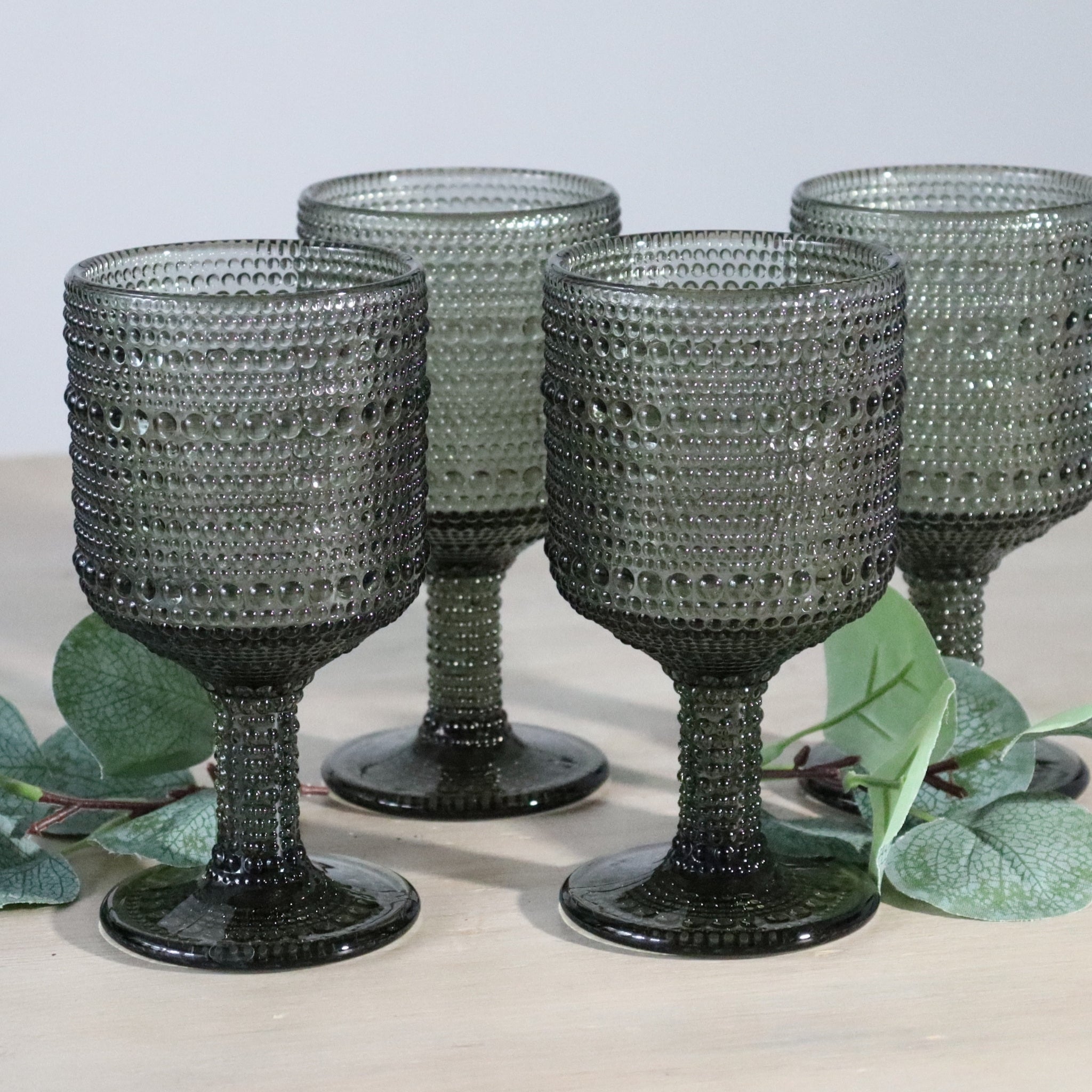 4 grey textured wine goblets with leafy surroundings
