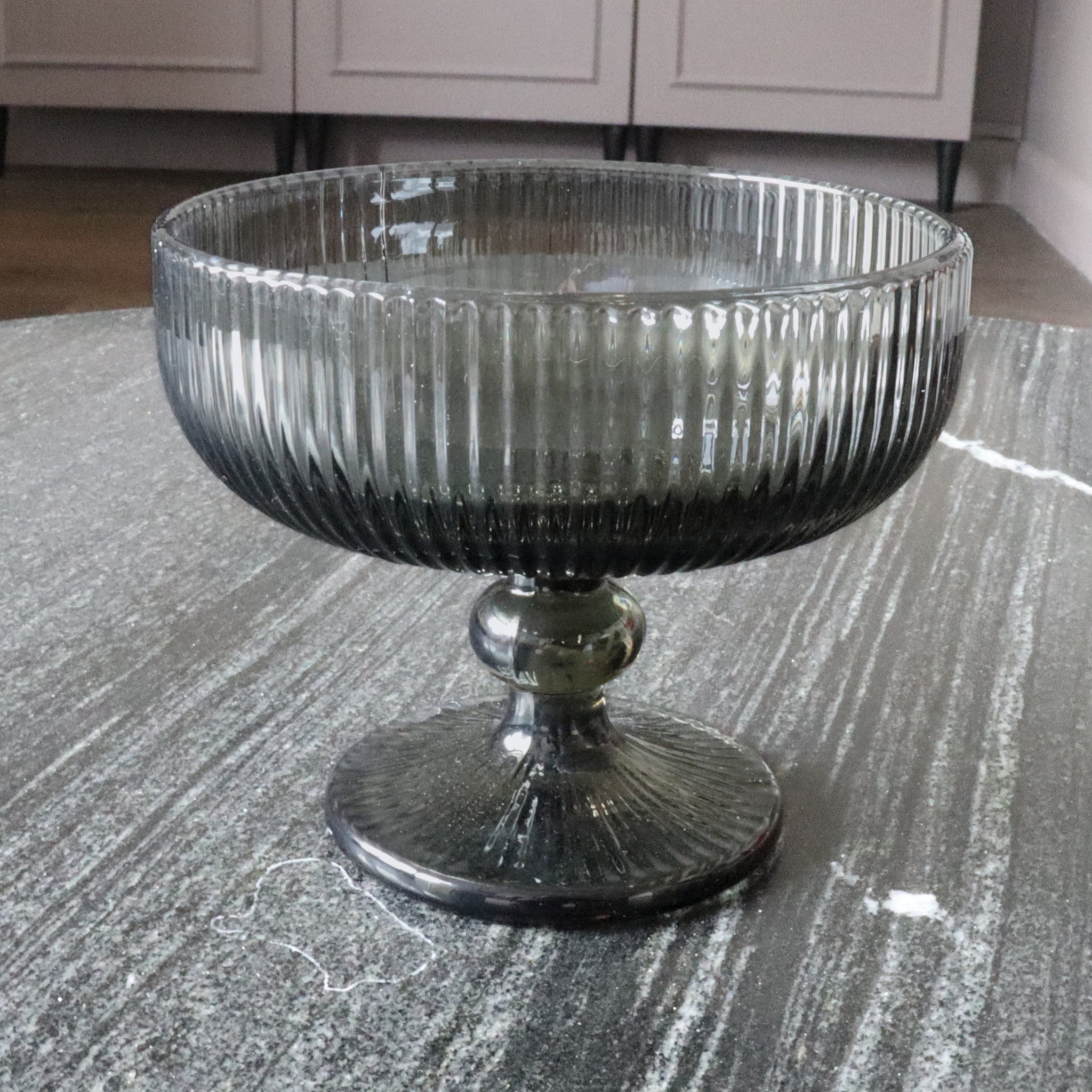 Decorative glass bowl on a textured surface with a neutral background