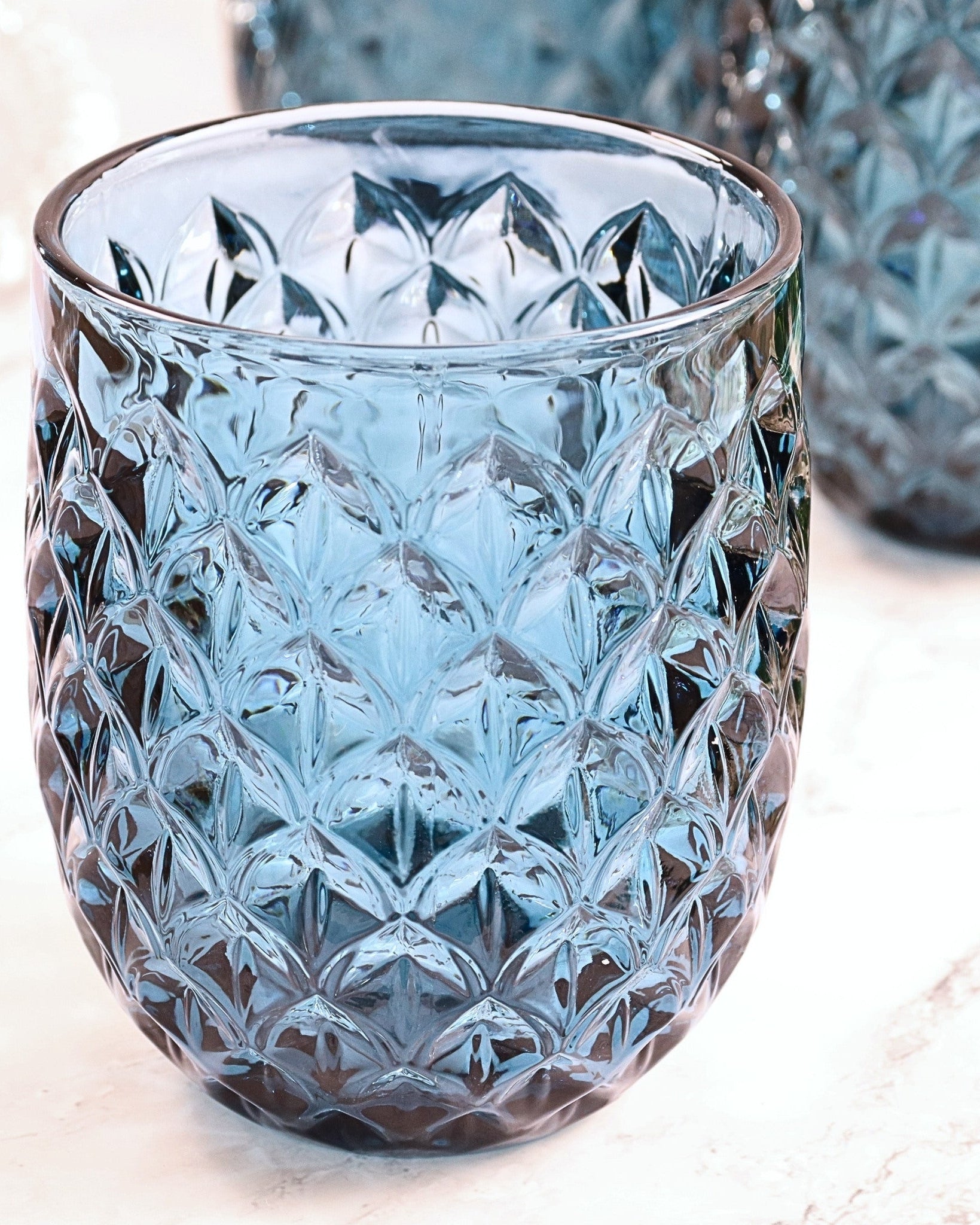 Crystal glass tumbler with diamond pattern on a light surface