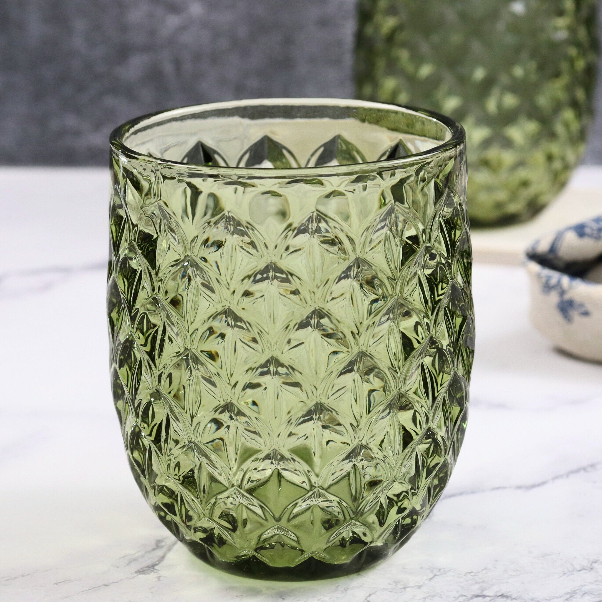 Green textured glass tumbler on a marble surface