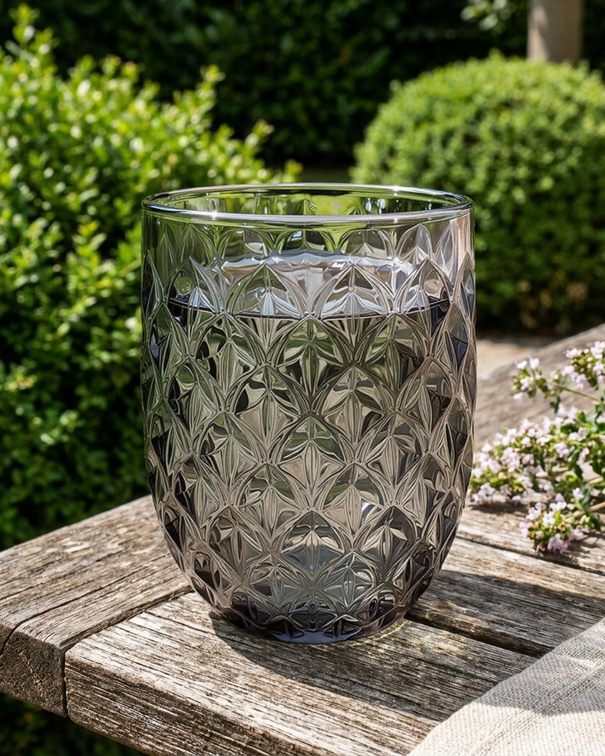 Decorative glass vase with geometric pattern on a wooden surface outdoors